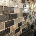 A close-up of a kitchen backsplash featuring textured mosaic tiling in a range of neutral colors.