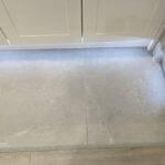 View of a threshold with a stone floor transitioning from a wooden surface to a bathroom tiling area.
