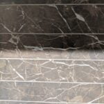 Close-up of brown marble bathroom tiling steps with white veining patterns.