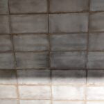Aged bathroom tiling wall with signs of wear and discoloration.