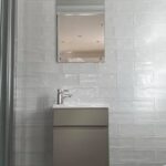 Modern bathroom interior featuring a wall-mounted sink, a mirror, and elegant porcelain tiling.