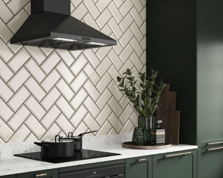 Modern kitchen with green cabinets, marble countertop, mosaic tiling backsplash, and black range hood.