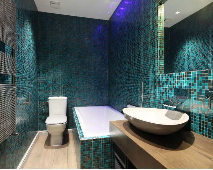 Modern bathroom with blue natural stone tiling, a white freestanding bathtub, and ambient lighting.