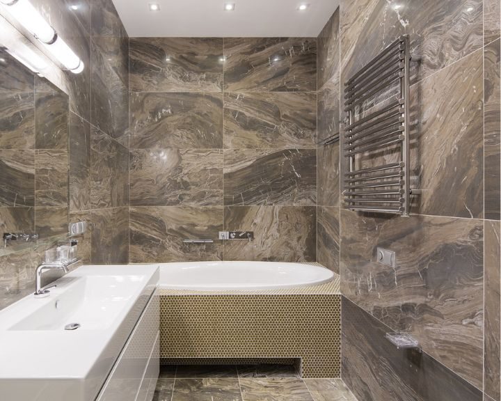Modern bathroom interior with porcelain tiling, featuring a built-in bathtub and a heated towel rail.