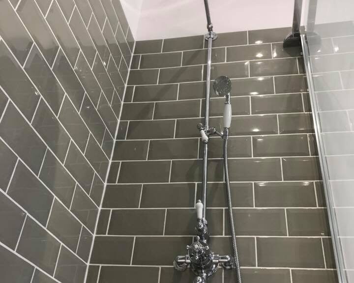 Modern bathroom shower with gray tiles and stainless steel fixtures.