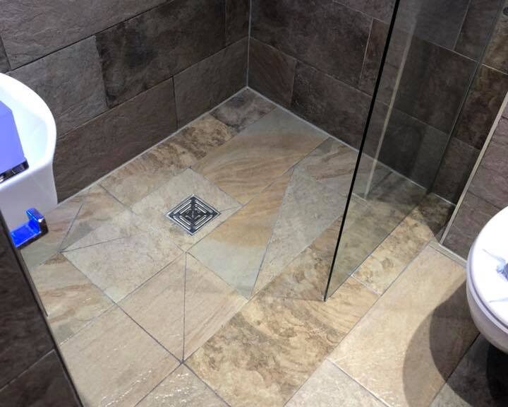 A modern walk-in shower with glass panels and porcelain tiling on walls and floor.